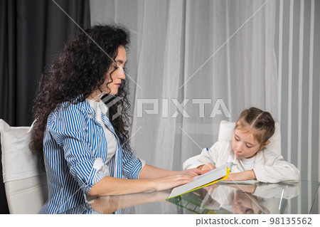 Nervous mother helps daughter with doing homework at home Nervous mother helps daughter with doing homework at home 98135562