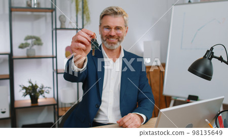 Mature man real estate agent showing the keys of new home house apartment buying or renting property 98135649