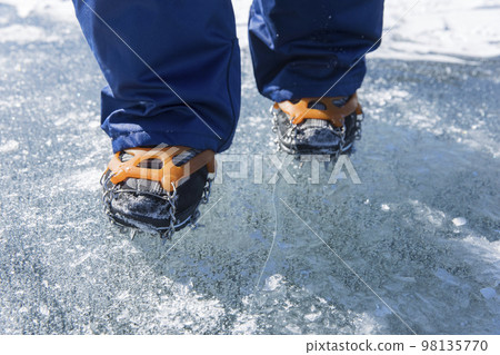 穿著鏈釘在冰上行走的孩子的腳 穿著鏈釘在冰上行走的孩子的腳 98135770