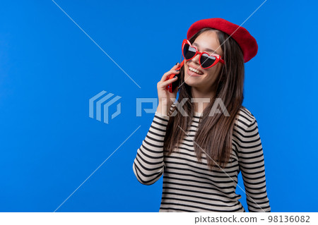Stylish french woman talking by phone, nice joke, smiling. Young lady on blue background. Having 98136082