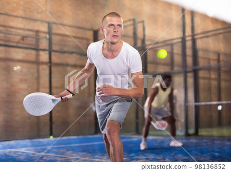 Concentrated paddle tennis player preparing to hit forehand Concentrated paddle tennis player preparing to hit forehand 98136852