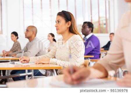 Focused hispanic woman on lesson in school auditorium 98136976