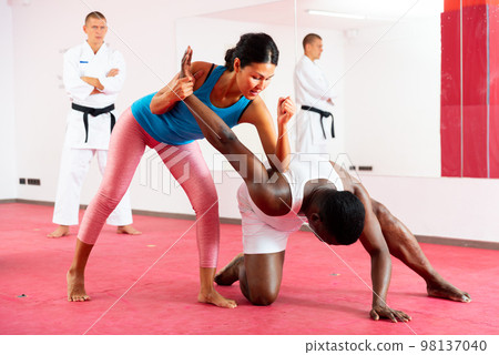 Man and woman during self defense training at sports gym Man and woman during self defense training at sports gym 98137040