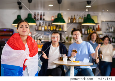 Sad girl with friends upset by the loss of her favorite team of Netherlands Sad girl with friends upset by the loss of her favorite team of Netherlands 98137131