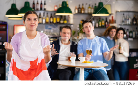 Company of young adult sports supporters with national flag of England upset about favorite team losing match in bar 98137269