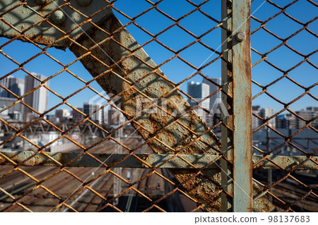 Rusted fence of the Mitaka overpass in the suburbs of Tokyo Train depot over the wire mesh and blur around Mitaka station 2022.12 Rusted fence of the Mitaka overpass in the suburbs of Tokyo Train depot over the wire mesh and blur around Mitaka station 2022.12 98137683