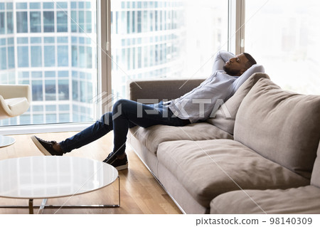 In luxury hotel African guy relax leaned on couch cushions 98140309