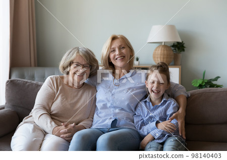 Girl and senior women of female generations resting on couch Girl and senior women of female generations resting on couch 98140403
