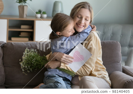 Happy peaceful young mom hugging adorable daughter with love 98140405