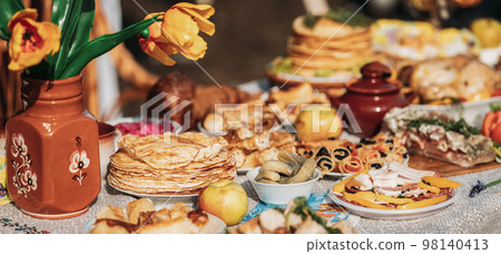 Dishes of the traditional Belarusian cuisine - pancakes, pancakes with caviar, lard, bacon, honey and pickled cucumbers. Attribute of traditional folk celebration of Maslenitsa. Panorama, Panoramic Dishes of the traditional Belarusian cuisine - pancakes, pancakes with caviar, lard, bacon, honey and pickled cucumbers. Attribute of traditional folk celebration of Maslenitsa. Panorama, Panoramic 98140413