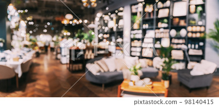 Home accessories and household products in store of shopping centre. View of home accessories for living room in shop fashion retail store. Sofa with pillows, table with cups. Home plant in flower pot 98140415