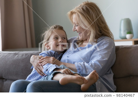 Positive mature grandma holding grandkid girl in arms on lap 98140467