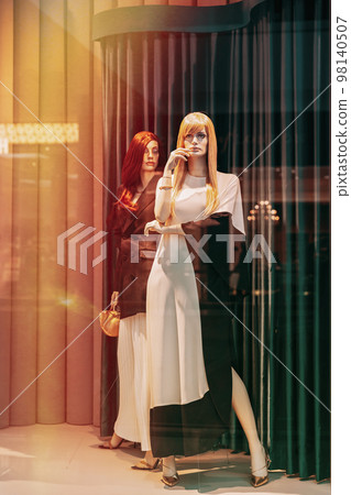 Female mannequin in shop window showcase of store mall market. Fashion clothes - dress, jacket. Mannequins dressed in female woman fashion clothes in store of shopping center. Showcase store. Flare 98140507