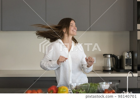 Happy beautiful woman dancing alone in modern kitchen Happy beautiful woman dancing alone in modern kitchen 98140701