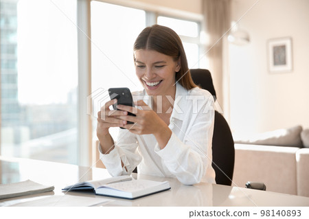 Woman holding smartphone seated at desk with paper organizer Woman holding smartphone seated at desk with paper organizer 98140893