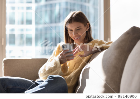 Beautiful young woman rest on sofa use mobile phone Beautiful young woman rest on sofa use mobile phone 98140900