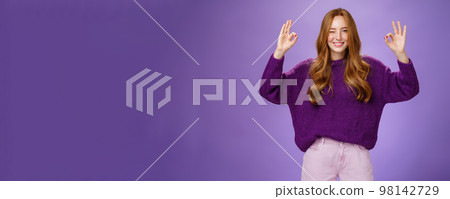 Relax everything ok. Assured charming and happy young redhead with long beautiful hair and freckles winking joyfully smiling and showing okay gestures with raised hands, affirming everything perfect Relax everything ok. Assured charming and happy young redhead with long beautiful hair and freckles winking joyfully smiling and showing okay gestures with raised hands, affirming everything perfect 98142729