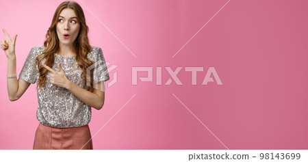 Wow interesting. Portrait amazed intrigued attractive young 20s girl shopping curious see cool promo folding lips widen eyes thrilled looking pointing left sideways, standing pink background 98143699