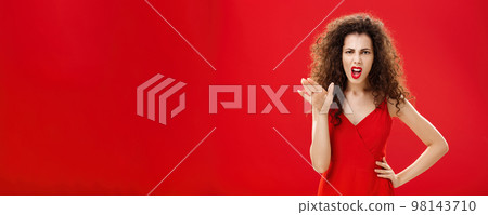 Girl chowing her temper to employees being fed up with unappropriate behaviour complaining standing pissed and dissatisfied gesturing with palm and holding hand on hip over red background 98143710