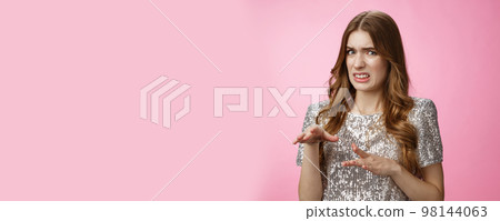 Disgusted reluctant young arrogant glamour woman telling about creepy man cringing aversion grimacing dislike gesturing displeased, expressing antipathy standing pink background freaked-out 98144063