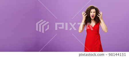 Woman getting annoyed and pissed employees spoiling her perfomance. Portrait of outraged furious female musician in red evening dress raising clenched fists grimacing and yelling angry Woman getting annoyed and pissed employees spoiling her perfomance. Portrait of outraged furious female musician in red evening dress raising clenched fists grimacing and yelling angry 98144131