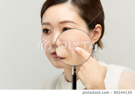 女人的皮膚被放大鏡放大。 98144139