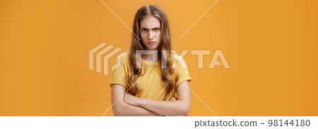 Girl mad like devil. Portrait of angry bothered and offended hateful young woman looking from under forehead frowning and sulking crossing arms against chest in defensive pose, scorning offender 98144180