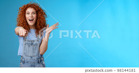 Excited impressed surprised cute redhead european woman curly astonished happily pointing index finger camera gesturing lively thrilled see awesome thing reacting amazed standing blue background 98144181