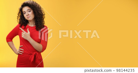Upset disappointed and unimpressed attractive young european curly-haired woman in red dress pursing lips in gloomy face, frowning displeased as pointing at upper left corner from regret and dislike Upset disappointed and unimpressed attractive young european curly-haired woman in red dress pursing lips in gloomy face, frowning displeased as pointing at upper left corner from regret and dislike 98144235