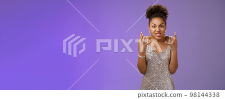Annoyed pissed arrogant freak-out african american woman in silver dress squeeze fists angry frowning grimacing anger furiously look camera bothered yell rage react outrageous disrespect 98144338