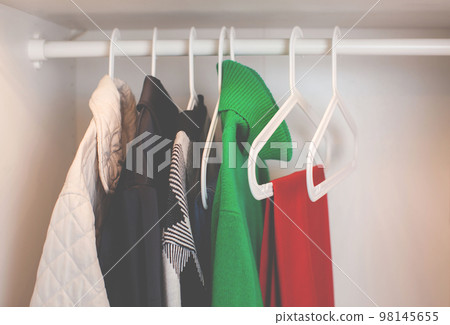 Clothes hang on a hanger in the closet. 98145655