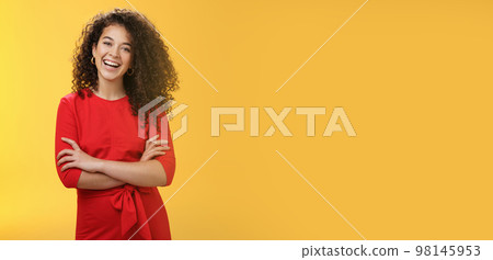 Self-assured happy enthusiastic curly-haired female reporter in cute red dress laughing carefree, having fun tilting head amused and holding hands crossed over body in confident pose over yellow wall Self-assured happy enthusiastic curly-haired female reporter in cute red dress laughing carefree, having fun tilting head amused and holding hands crossed over body in confident pose over yellow wall 98145953