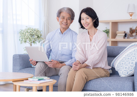 A middle-aged couple chatting while looking at a computer 98146986