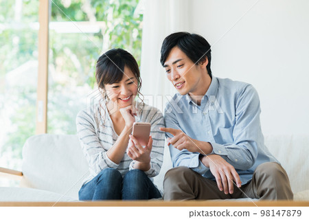看智能手機的一對年輕夫婦 98147879