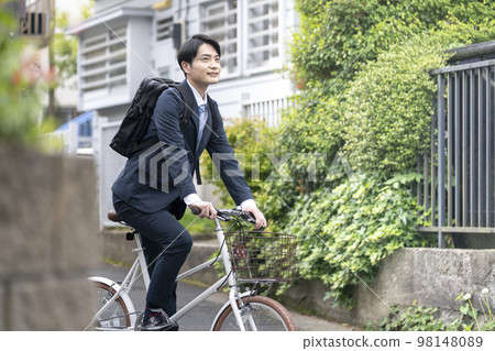 Young man in a suit riding a bicycle Young man in a suit riding a bicycle 98148089