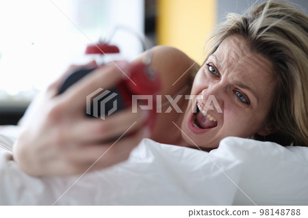 Woman looks at alarm clock and yells to bed Woman looks at alarm clock and yells to bed 98148788