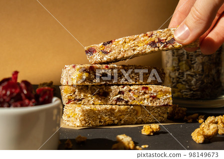 Woman takes Homemade Granola energy bar. Variety of protein granola breakfast bars, with nuts, raisins dried cherries and chocolate. Healthy nutrition eating Gluten free cereal dieting snack super Woman takes Homemade Granola energy bar. Variety of protein granola breakfast bars, with nuts, raisins dried cherries and chocolate. Healthy nutrition eating Gluten free cereal dieting snack super 98149673