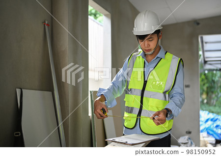 Civil engineer wearing hardhat examining plans at construction site. Engineer, construction concept 98150952