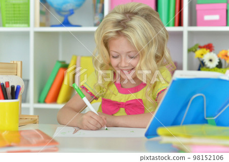 little girl studying at home at the table 98152106
