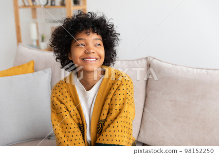 Cheerful Young African Woman Holding A Pillow And Sitting On The