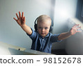 Smiling little boy in headphones studying online using laptop at home, cute happy little kid in headphones taking internet lesson or lesson on computer, home learning concept 98152678
