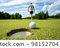 Hole on the golf course, next to a white ball 98152704