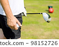 Close up of male golfer's hands holding golf club on green grass. Autumn 98152726