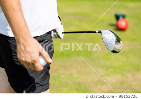 Close up of male golfer's hands holding golf club on green grass. Autumn Close up of male golfer's hands holding golf club on green grass. Autumn 98152726