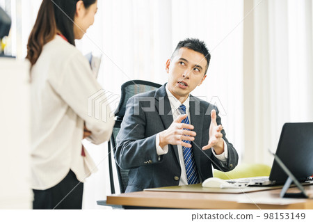 Businessman talking to colleague in office 98153149