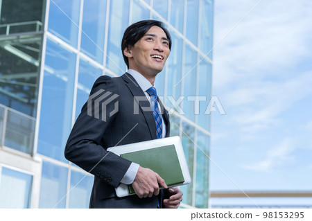 Portrait of businessman standing in front of office building 98153295