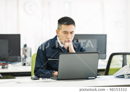 一個穿著工作服的男人在辦公室看電腦時很擔心 98153332