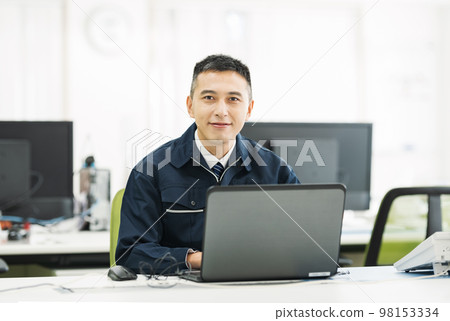 Portrait of a man in work clothes doing office work on a computer 98153334