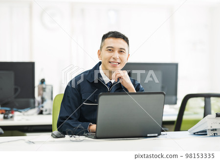 Portrait of a man in work clothes doing office work on a computer Portrait of a man in work clothes doing office work on a computer 98153335