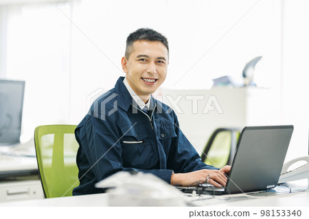 Portrait of a man in work clothes doing office work on a computer Portrait of a man in work clothes doing office work on a computer 98153340